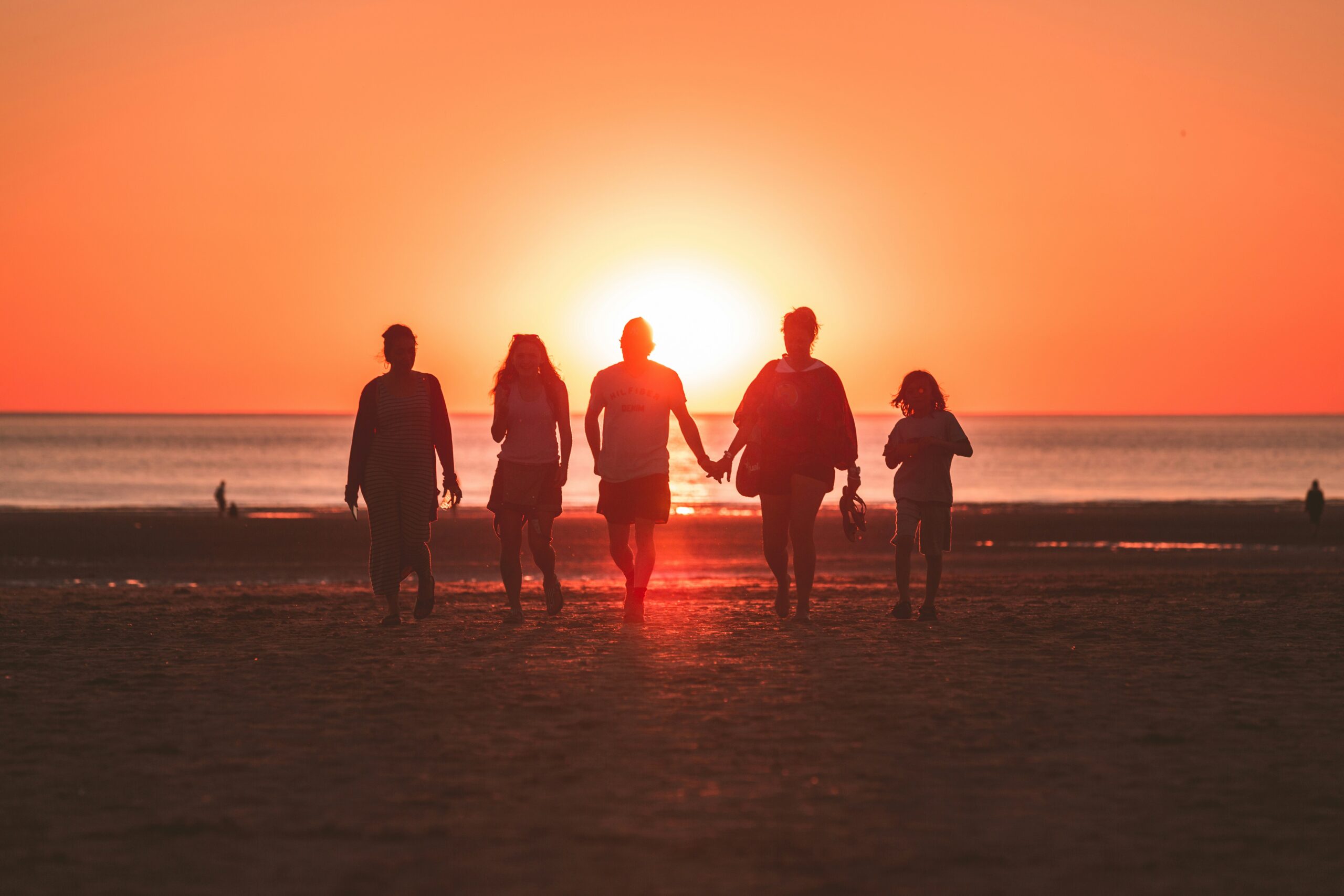 kevin-delvecchio-7noZJ_4nhU8-unsplash Family walking on the beach during sunset near the best luxury group accommodation in Darwin